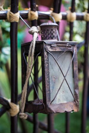 Antique rusty metal lantern hanging on a fenceの写真素材