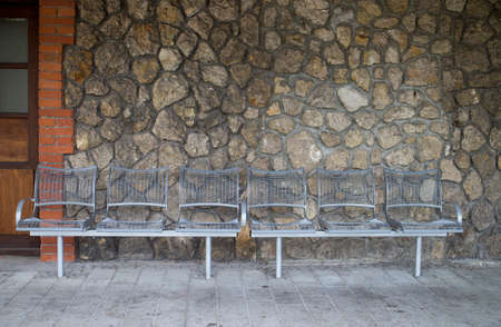 Metal bench in the waiting area on the platform of a train stationの写真素材