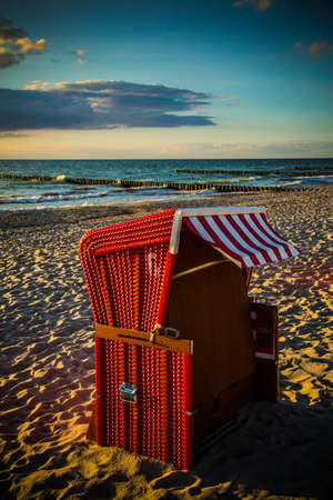 Red traditional beach chair in the sand on the beach of the Baltic Sea at sunsetの写真素材