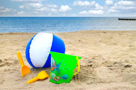 Ball and toys on the sunny summer beach with the sea and sky in the backgroundの写真素材