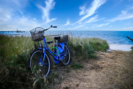 Blue bicycle on a sand dune with the beach and sea in the backgroundの写真素材