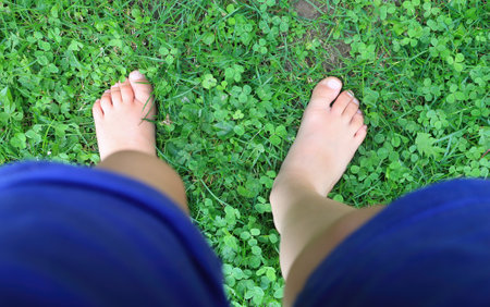 Little girl standing bare feet in the grassの写真素材