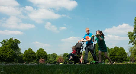Father and his children walk under blue sky in one of the many local parks of London 