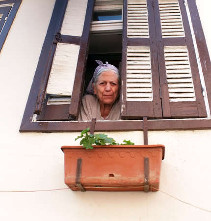 Elderly woman looks through windowのeditorial素材