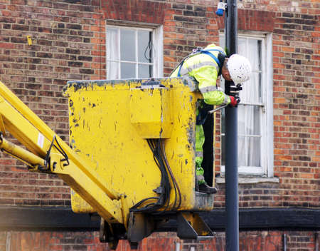 Council worker painting the pole of a street lampのeditorial素材