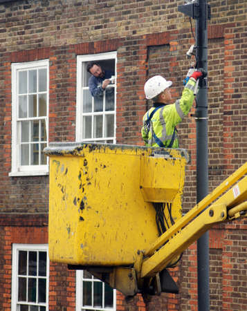 Council worker painting the pole of a street lampのeditorial素材