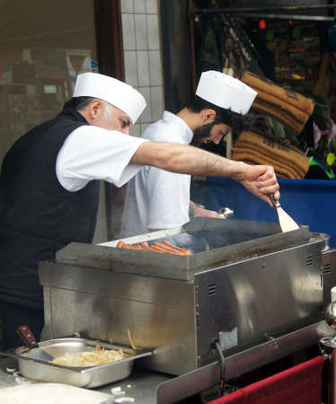 Two cook cooking sausagesのeditorial素材