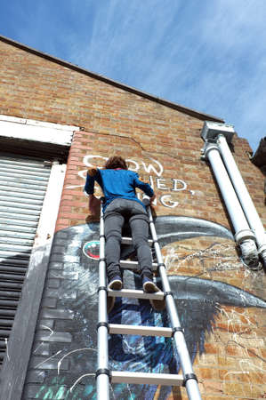 Graffiti artist paints the building wallのeditorial素材