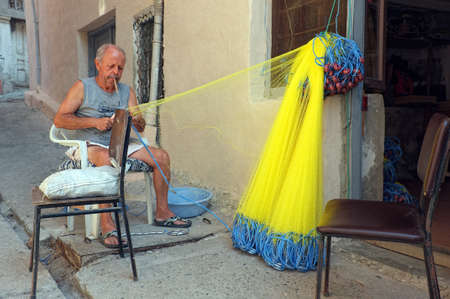 Elderly fisherman mending his fishnetのeditorial素材