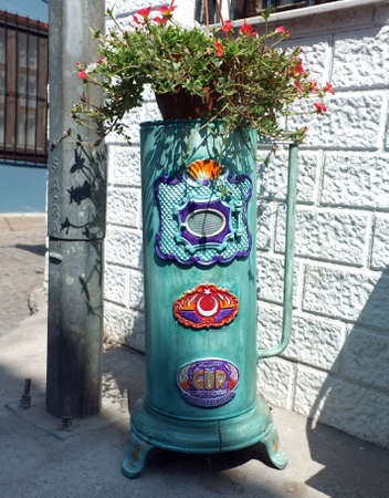 Painted and decorated old stove wit a plant on top of it.のeditorial素材