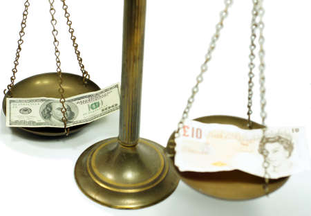 Pound and dollar notes on scale in a conceptual photoの写真素材