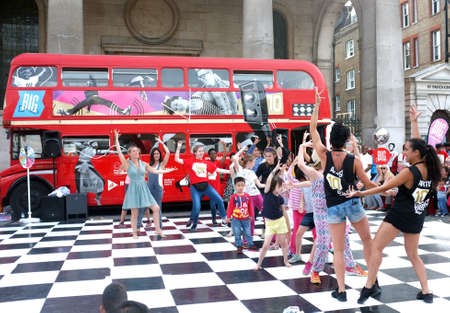 Group of people dance in front of a London bus as part of a promotional campaign of a brand in Covent Garden, London.のeditorial素材
