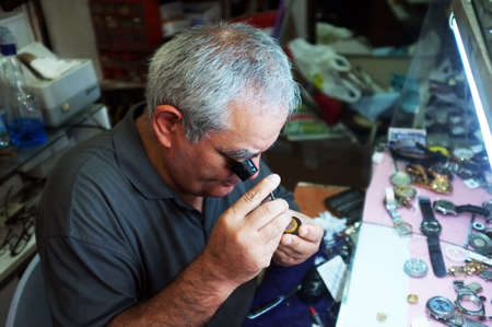Traditional watchmaker  repairs a watch with magnifier in Edremit, Turkey.のeditorial素材