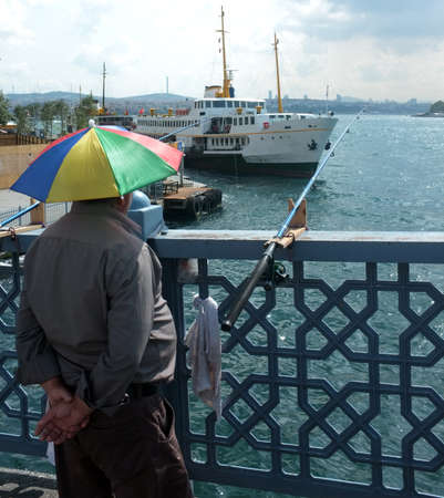 Man waits to catch fish on Galata Bridge by Bosphorus in Istanbul, Turkeyのeditorial素材
