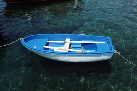 Blue small boat floating on waterの写真素材