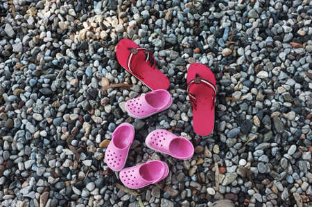 Three pairs of slippers on pebblesの写真素材