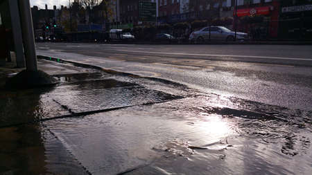 Burst pipe causes flooding on street in London, UKのeditorial素材