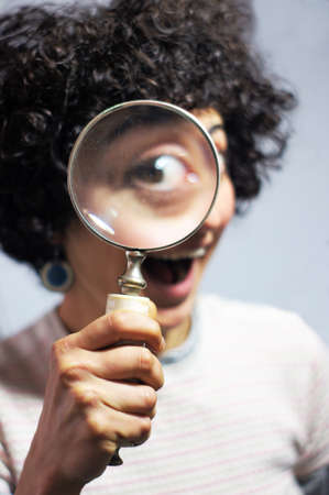 Woman holding and looking through a magnifierの写真素材