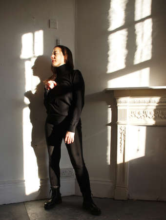 Woman standing indoors with shadows and sunlight effectsの写真素材
