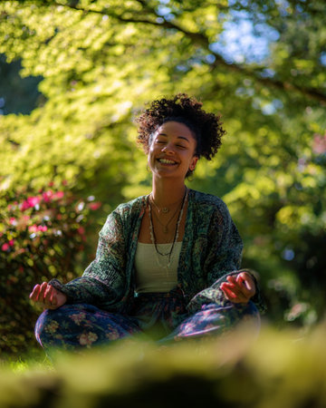 Portrait of a beautiful young african american woman meditating in the parkの素材