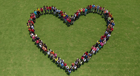 A large group of people forming a heart shape on a green lawnの素材