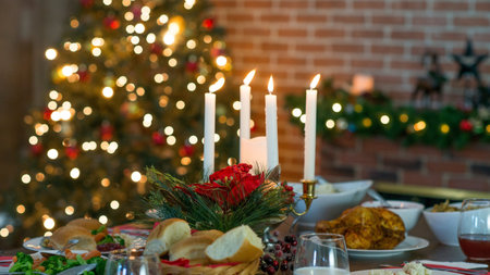 Christmas dinner table with candles in the living room with a Christmas treeの素材