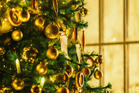 Christmas tree with gold ornaments on the blurred background of the windowの素材