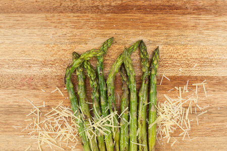 Fresh grilled asparagus and parmesan cheese on a timber board の写真素材