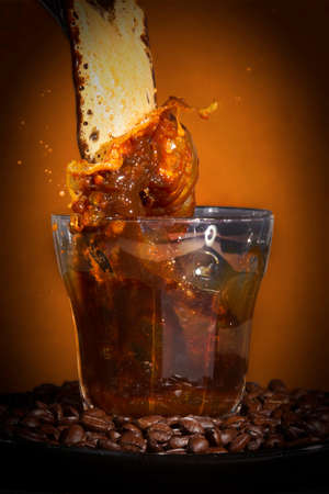 Coffee beans and coffee splashing in a glass on a dark background.の写真素材