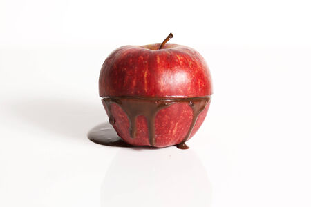 Cut apple with dark chocolate oozing out with a white background.の写真素材