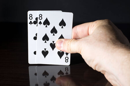 Playing cards, a pair held in a hand on a dark background.の写真素材
