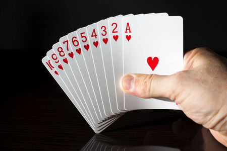 Playing cards, a run held in a hand on a dark background.の写真素材
