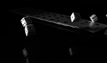 High contrast black and white image of gaming dice and a row of playing cards.