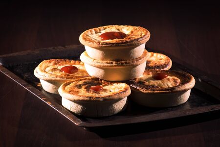Freshly baked meat pies with sauce and high contrast lighting.の写真素材