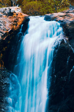 Waterfall with orange and red colours in the Gold Coast hinterlands on the Queensland and New South Wales border.の写真素材