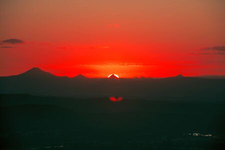 Silhouette of the sun and the mountains. View from Mount Tamborine.の写真素材