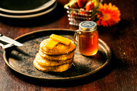 Toasted crumpets with honey drizzled over them and strawberries in the background.の写真素材