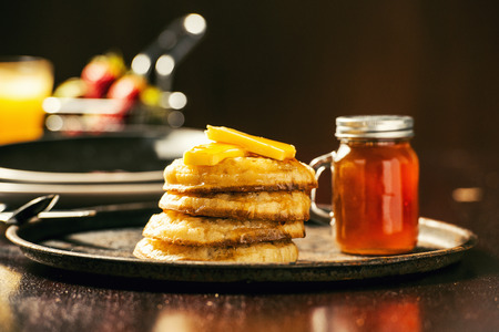 Toasted crumpets with honey drizzled over them and strawberries in the background.の写真素材