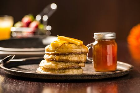 Toasted crumpets with honey drizzled over them and strawberries in the background.の写真素材