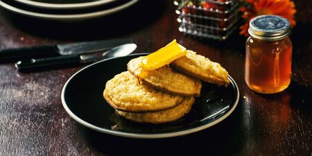 Toasted crumpets with honey drizzled over them and strawberries in the background.の写真素材