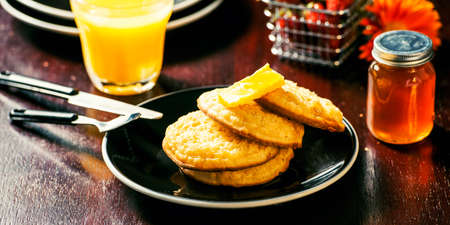 Toasted crumpets with honey drizzled over them and strawberries in the background.の写真素材