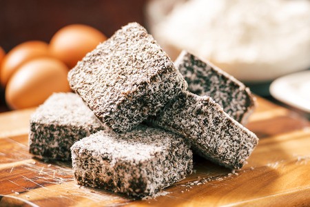 Group of Lamingtons on a timber cutting board with food ingredients in the backgroundの写真素材