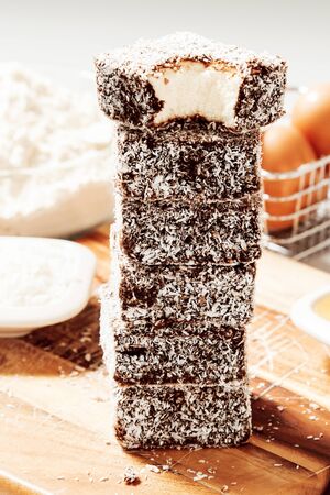Group of Lamingtons on a timber cutting board with food ingredients in the backgroundの写真素材