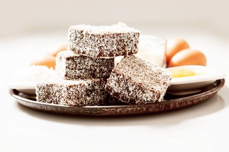 Group of Lamingtons on a timber metal baking tray with food ingredients in the backgroundの写真素材