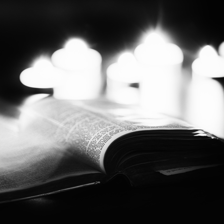 Bible with candles in the background. Low light high contrast black and white image.の写真素材