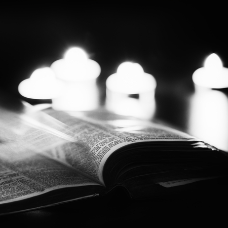 Bible with candles in the background. Low light high contrast black and white image.の写真素材