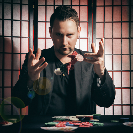 Concept: A high stakes poker player is winning big and feeling a little to confident against his opponents. He becomes overconfident and arrogant, showing of his chip stakes. Cinematic portrait.の写真素材