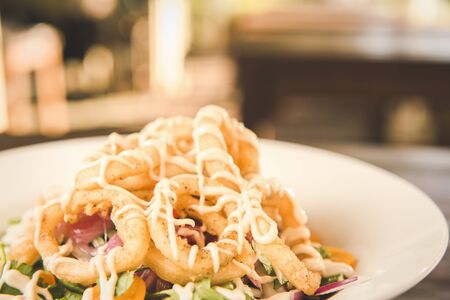 Calamari deep fried served with salad in white bowl on a timber bench.の写真素材