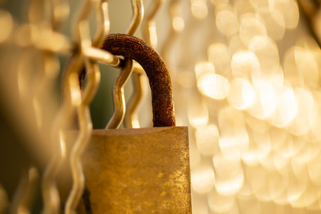 Closeup of a rusted padlock with golden bokehの写真素材