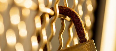 Closeup of a rusted padlock with golden bokehの写真素材